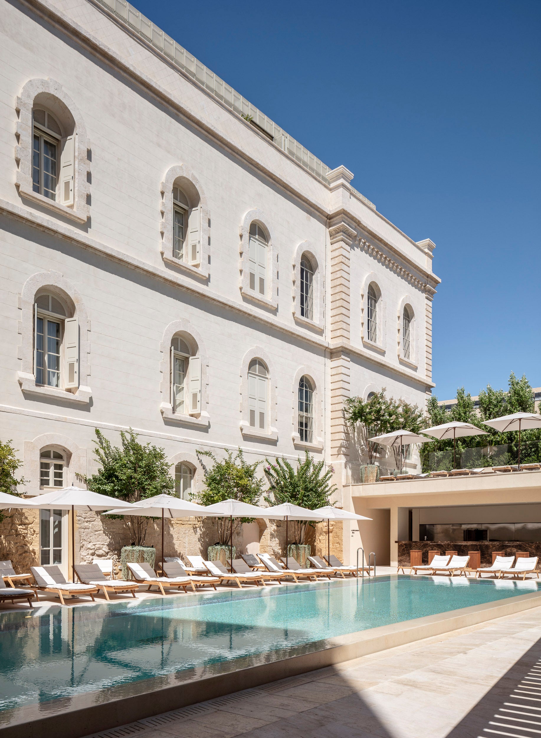 Luxury hotel pool area with classical architecture and clear blue sky